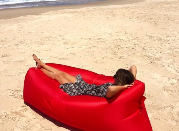 person lying on their back in inflatable air lounge on the beach